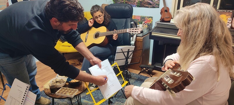 מורה לגיטרה מסביר לתלמיד בחוברת לימוד אקורדים